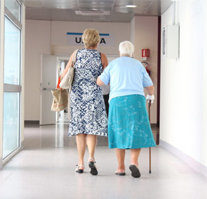 Daughter helping mother into hospital